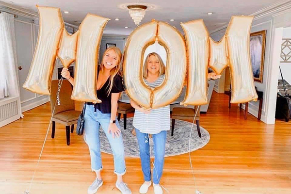 Greek mother and daughter holding 'mom' sign.